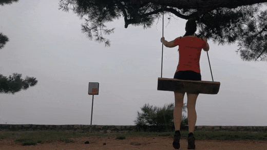 A woman on a swing moves away and returns through reversed frames in a ping-pong GIF